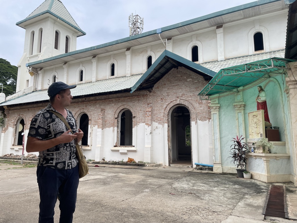 Sylvain, historien indépendant, devant une ancienne église de style colonial au Laos